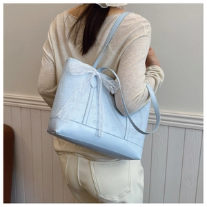 Detail of light blue tote bag with embossed cartoon characters and white lace bow