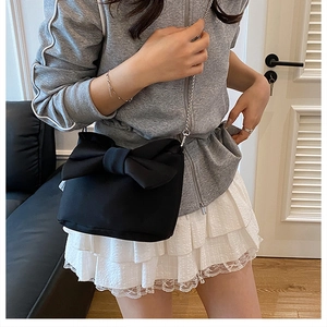 Détail d'un sac à nœud noir avec chaîne argentée dans un intérieur minimaliste