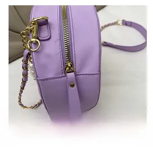 Detailed close-up of smooth gold zipper and premium pearl decor on purple round bag