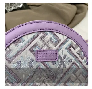 Close-up of pearl chain handbag showing purple leather trim and woven fabric pattern
