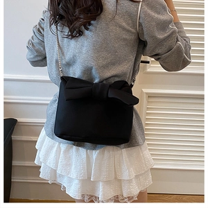 Detailed back view of a black crossbody bag with large bow and silver chain strap