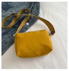 Detail of yellow lightweight nylon crossbody bag on denim jacket with broad strap