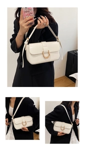 Detail of white glossy underarm bag featuring a gold U-shaped hardware buckle