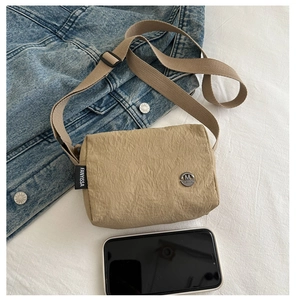 Close-up of khaki nylon shoulder bag with crinkled texture fabric and metal logo detail