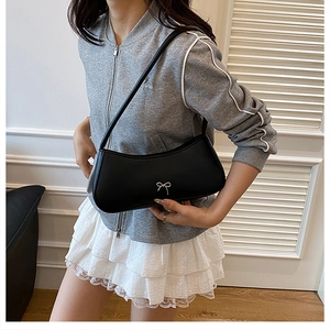 Chic black shoulder bag detail with a silver metal bow on high-quality synthetic leather