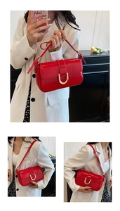 Detail of red patent leather baguette bag featuring a decorative gold U-shaped buckle