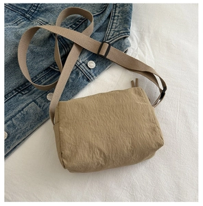 Detail of khaki nylon crossbody bag showing crinkled fabric texture and adjustable strap