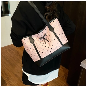 Detail of pink puffy tote bag with black heart embroidery and ribbon bow accessory
