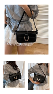 Detail of black baguette bag with gold horseshoe buckle and adjustable shoulder strap