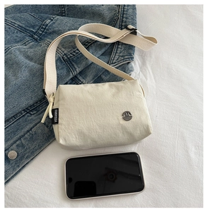 Detail of off-white crossbody bag featuring M Fashion badge and FANYISSA side woven label