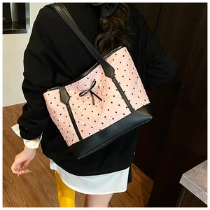Detailed view of pink tote bag with black heart patterns and chic bow knot detail