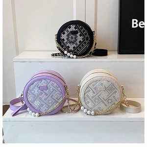 Detailed close-up of circular crossbody bags featuring geometric embroidery and pearl chains