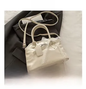 Détail du sac coquillage en PU blanc avec nœud en dentelle et téléphone pour échelle