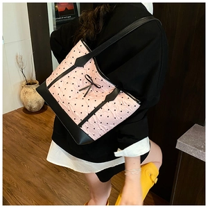 Detailed shoulder view of pink tote bag with black heart patterns and bow details