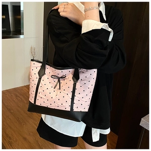 Detail of light pink tote bag with black heart patterns and small bow decoration