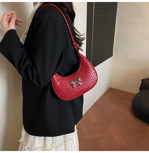 Detailed view of red woven texture on a crescent shoulder bag with silver bow buckle
