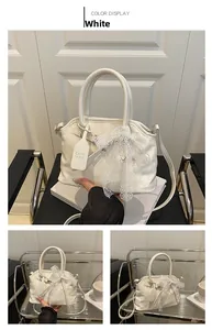 Détail du sac coquille blanc avec nœud en dentelle et fine bandoulière réglable