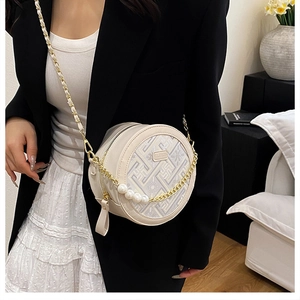Détail du sac rond beige avec motif géométrique, poignée en perles et logo mode en métal