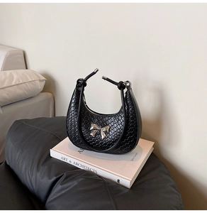 Detailed view of woven black crescent bag with silver bow and knot handle texture