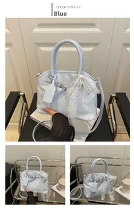 Détail du sac en cuir verni bleu avec nœud en dentelle et étiquette de logo