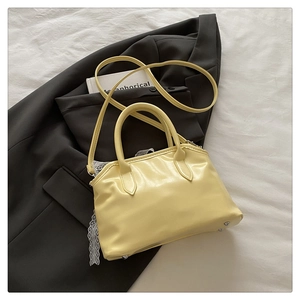 Détail d'un sac coquille jaune brillant montrant la poignée et les clous de protection