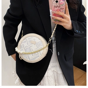 Detail of round beige crossbody bag with geometric pattern and pearl chain strap