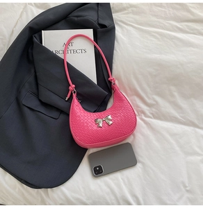 Close-up of rose pink crocodile embossed half-moon bag with silver metal bow detail