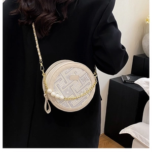 Detail of round cream crossbody bag with geometric pattern and pearl chain strap