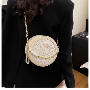 Detail of round beige crossbody bag featuring pearl chain and floral geometric patterns