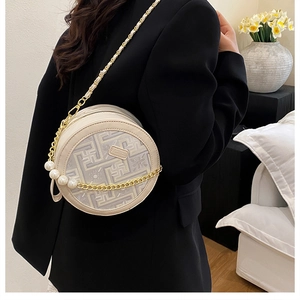 Detail of beige circular crossbody bag with geometric pattern and pearl chain strap