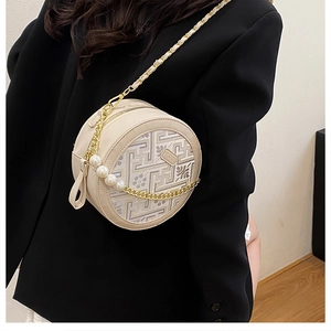 Detail of round embroidered crossbody bag with floral patterns and pearl chain strap