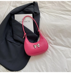 Detail of rose pink crescent bag with crocodile texture and silver bow buckle