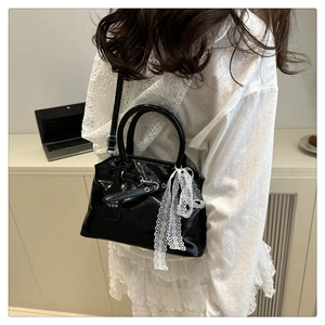 Détail du sac à main noir brillant orné d'un nœud en dentelle blanche élégant