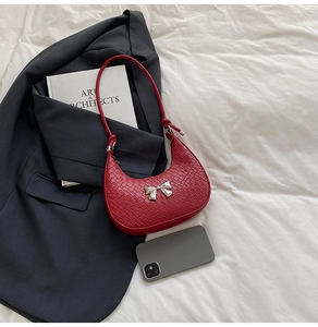 Close-up of red crocodile pattern shoulder bag with a silver metallic bow decoration