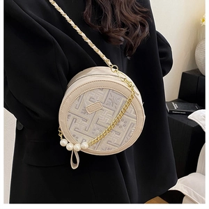 Detail of beige circular crossbody bag with jacquard fabric, chain strap and pearl charm