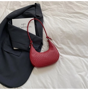 Detailed view of red crocodile pattern crescent bag with unique knotted strap detail