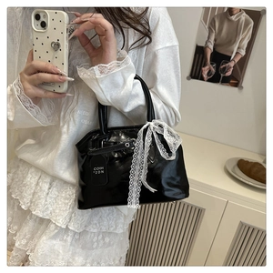 Gros plan d'un sac en cuir verni noir orné d'un nœud en dentelle blanche et étiquette