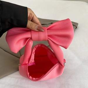 Pink satin handbag with a large 3D bow handle and metal chain for versatile crossbody wear