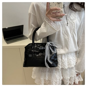 Détail d'un sac à main noir brillant orné d'un nœud en dentelle blanche élégant