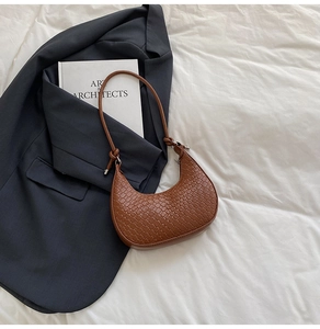 Detailed close-up of brown woven texture and knot detail on the crescent shoulder bag