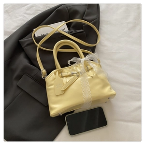 Détail du sac coquillage jaune clair avec nœud en dentelle blanche et bandoulière