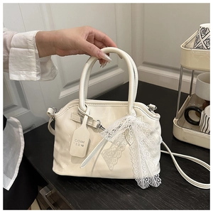 Détail du sac coquillage en cuir verni blanc avec nœud en dentelle et métal argenté