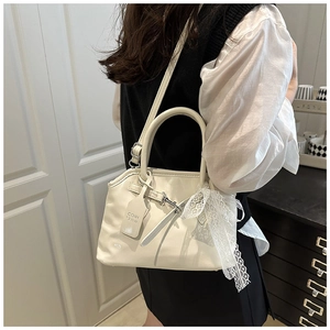 Détail du sac coquillage blanc crème brillant avec nœud en dentelle et étiquette chic