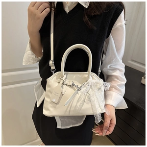 Détail du sac vintage blanc avec nœud en dentelle et étiquette en cuir porté en bandoulière