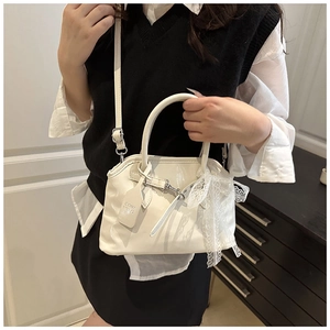 Détail du sac coquillage blanc brillant avec nœud en dentelle et boucle en métal