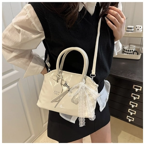 Détail du sac coquille crème avec nœud en dentelle délicat et texture en cuir verni brillant