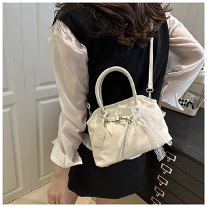 Vue détaillée du sac coquille blanc crème avec nœud en dentelle porté par un mannequin