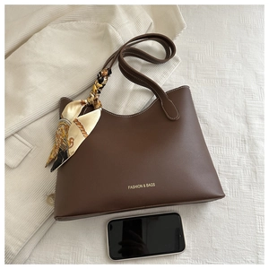 Détail d'un sac cabas marron avec surpiqûres blanches et foulard en soie décoratif