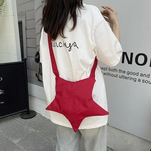 Vibrant red star-shaped canvas crossbody bag shown on a model in a stylish urban street setting