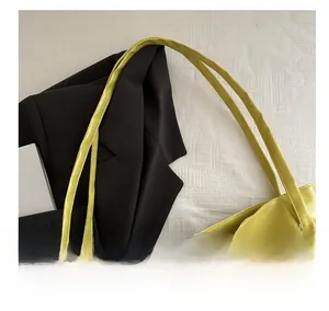 Detail of a bright yellow PU leather tote bag with a plush white cloud charm accessory